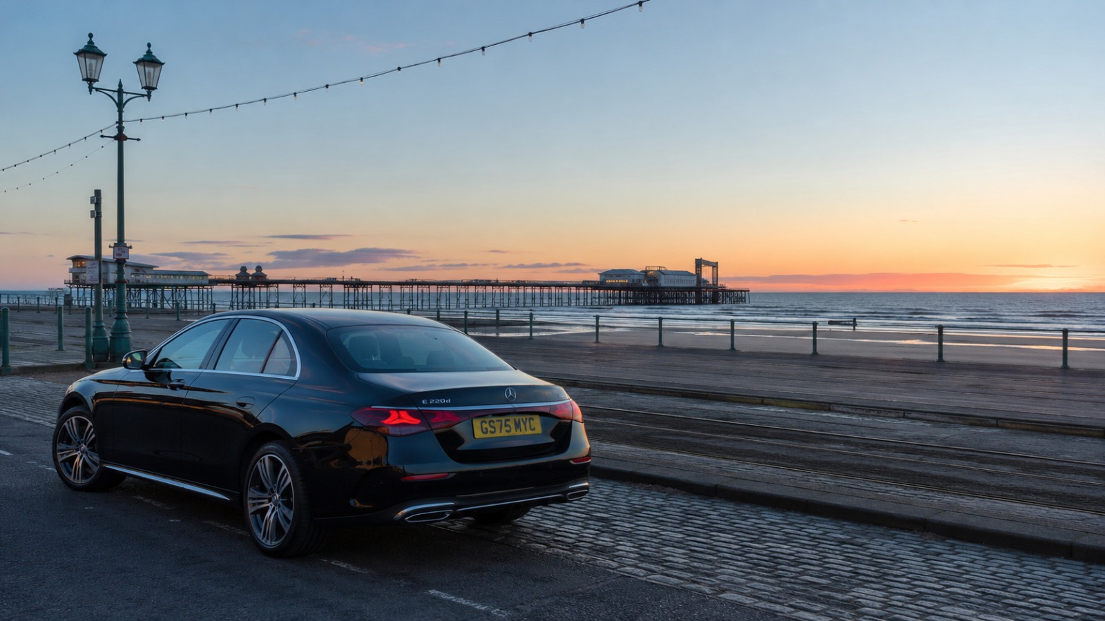 Executive saloon taxi at Blackpool at dawn on route to Manchester Airport, historic city architecture in background