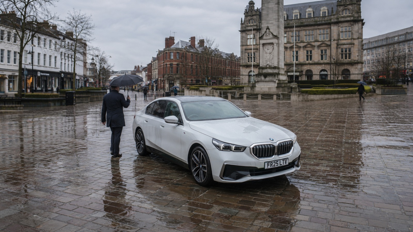White BMW saloon on rainy morning at Preston Flag Market Cenotaph for Manchester Airport departure