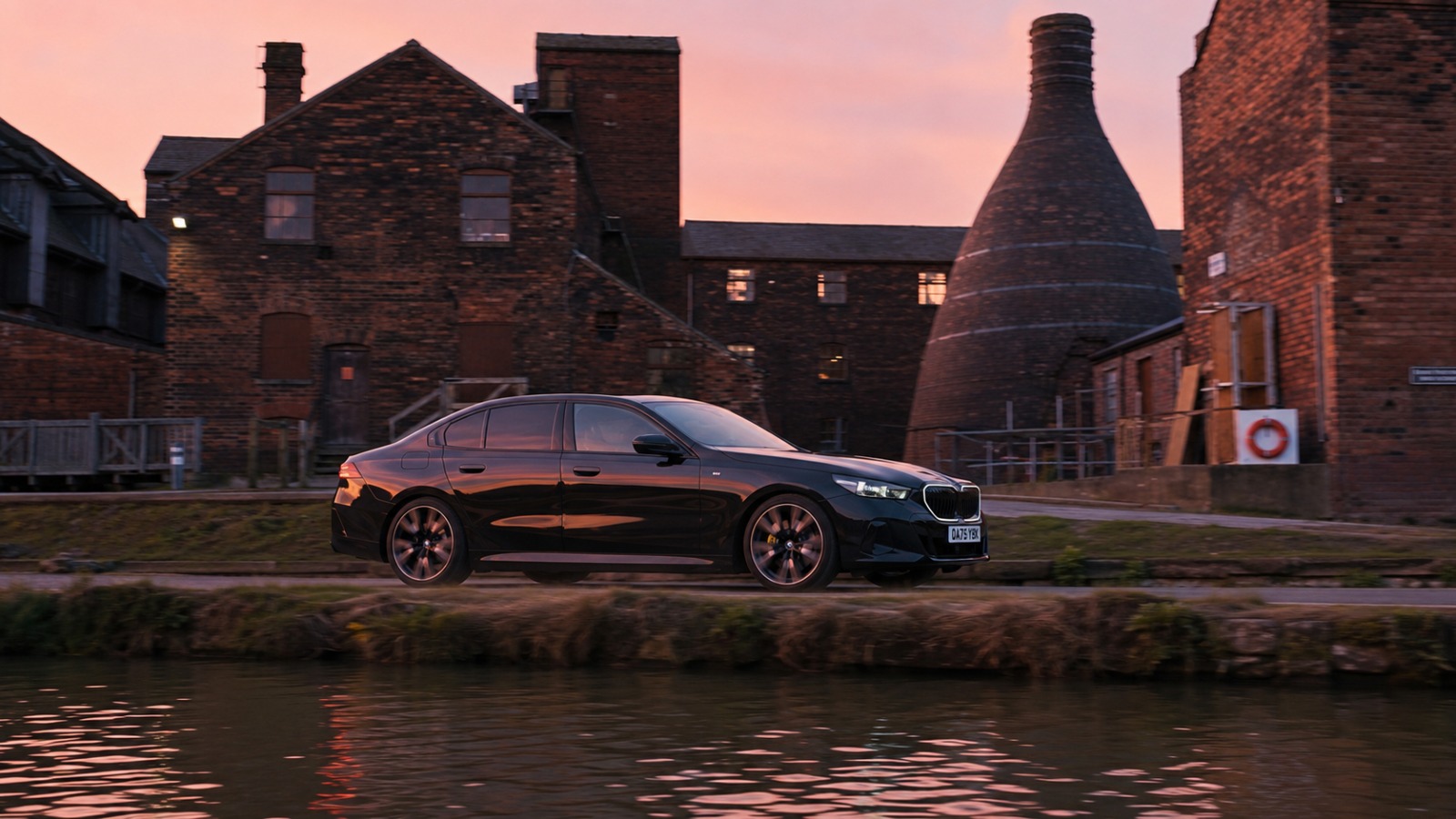 Executive saloon on canal-side road past Middleport bottle kilns at dawn, en route to Manchester Airport
