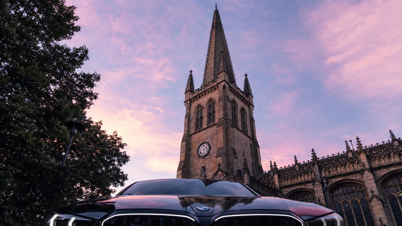 Wakefield Cathedral spire towering above BMW saloon at dawn for Manchester Airport departure